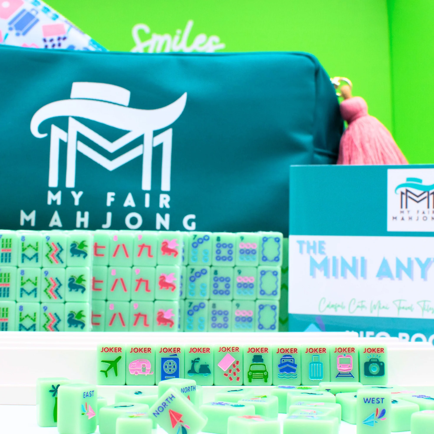 Green Go Anywhere mini mahjong set: teal carry-all bag with pink tassel, stacked tiles, jokers and wind tiles