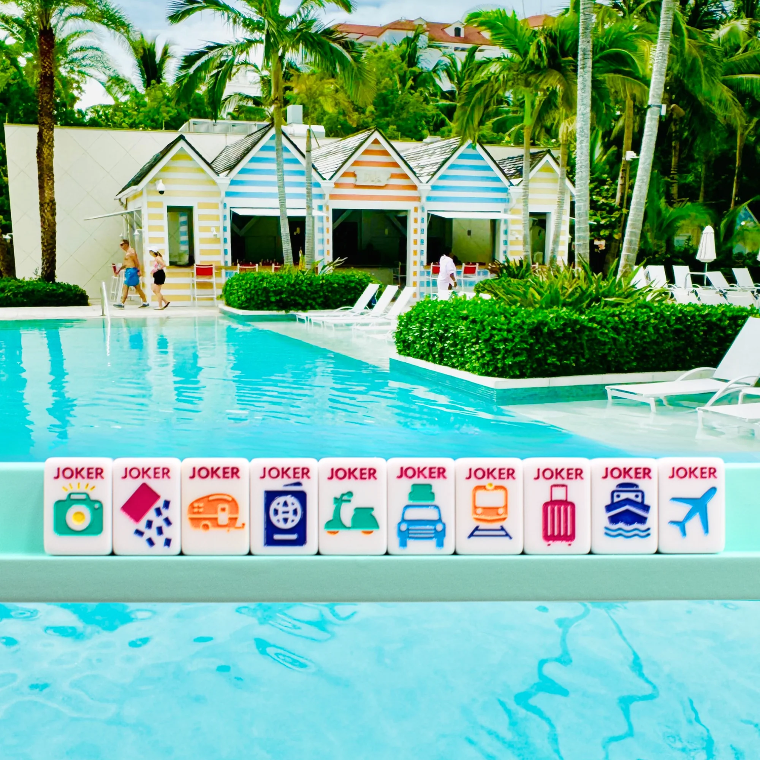 White Go Anywhere mini travel mahjong set: ten travel joker tiles on a mini rack by a resort pool
