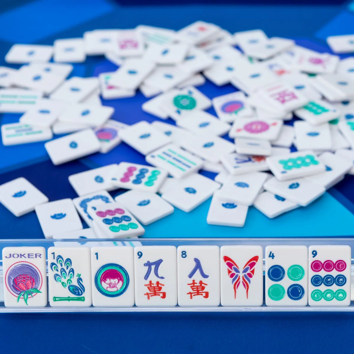Jewels White travel mahjong tiles on a clear rack with scattered tiles on blue
